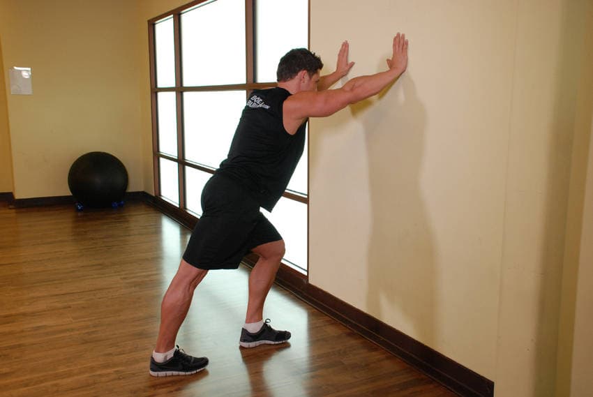 Calf Stretch Hands Against Wall, position 1 of 2