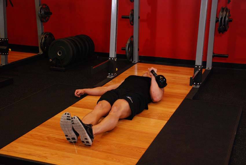 One-Arm Kettlebell Floor Press, position 1 of 2